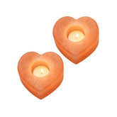 Two heart-shaped Himalayan salt candle holders, each with a lit tealight candle