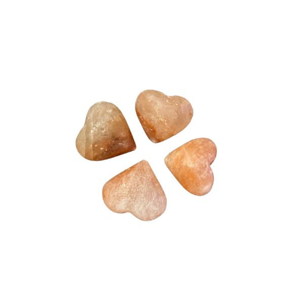 Four heart-shaped Himalayan salt massage stones on a white background