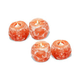 Four Himalayan salt candle holders, each with a lit tealight candle, on a white background