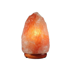 Natural Himalayan salt lamp glowing amber on a dark wood base against a white background