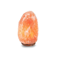 Natural Himalayan salt lamp glowing amber on a dark wood base against a white background