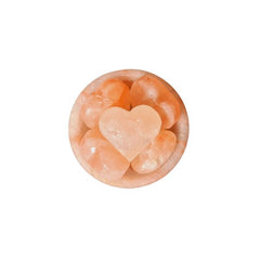 Himalayan salt fire bowl lamp filled with rock chunks and a heart-shaped stone, lit from below