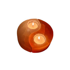 Pink and white Himalayan salt yin yang candle holder with two lit tealight candles on a white background
