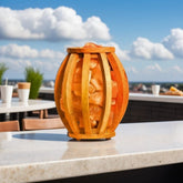 Barrel-shaped wood-slat salt lamp filled with pink Himalayan salt chunks on an outdoor rooftop counter