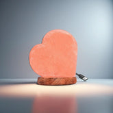 Heart-shaped Himalayan salt USB lamp on a wooden base against a dark blue backdrop
