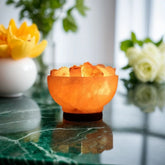 Lit Himalayan salt fire bowl lamp on a green marble table with yellow and white flowers