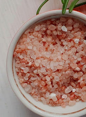 Close-up of coarse Himalayan pink salt crystals in a white bowl