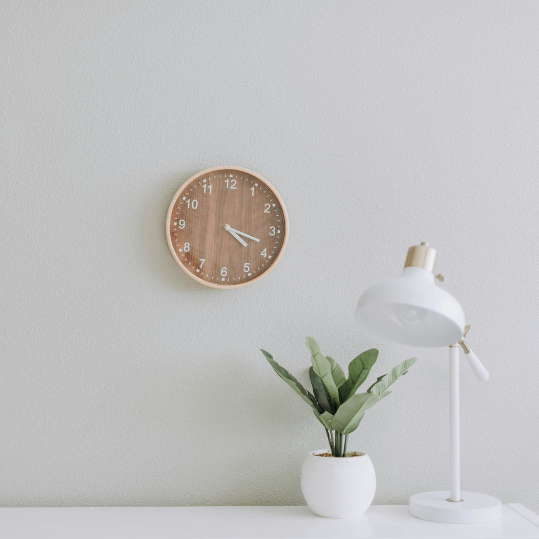 Small white desk lamp beside a potted plant, a compact lighting setup fit for tight apartments and dorms