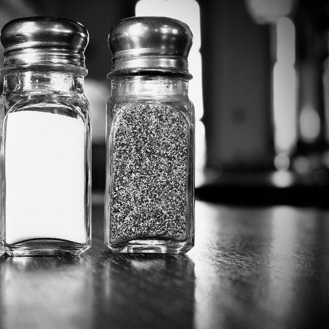 Two matching salt and pepper shakers on a counter, representing the switch from table salt to pink salt
