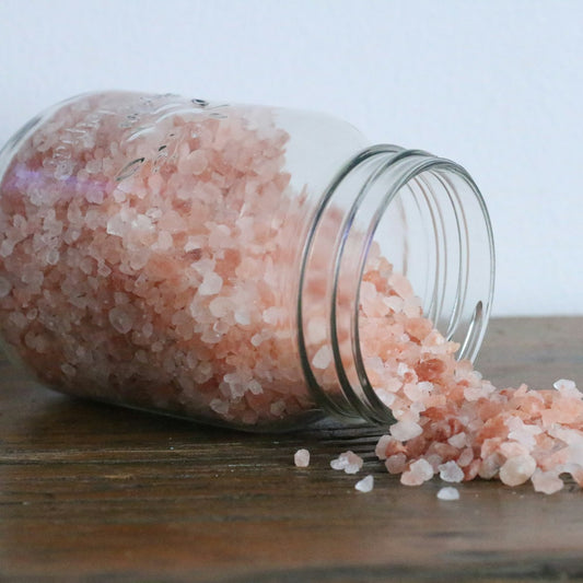 Coarse pink salt crystals in a clear glass jar, the kind used to make mineral bath soaks