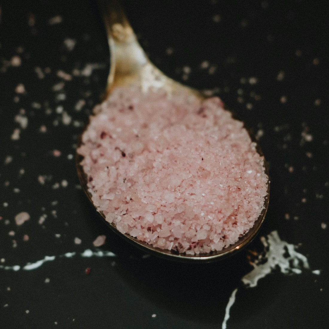 Pink Himalayan salt sprinkled while cooking, showing everyday culinary seasoning use