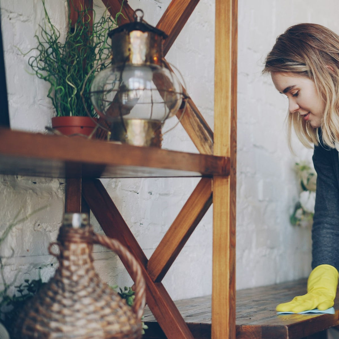 Gloved hand wiping a wooden surface with a cloth, similar to dusting a Himalayan salt lamp