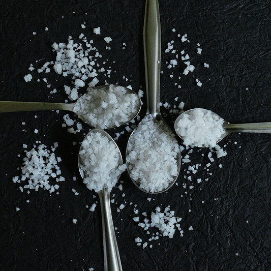Four spoons holding different salt varieties side by side for a home cook taste comparison