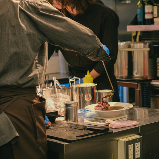 Chefs preparing food in a busy kitchen, seasoning dishes with Himalayan pink salt