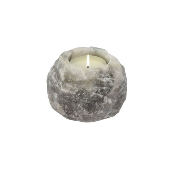 Grey Himalayan salt candle holder with a lit tealight candle against a white background