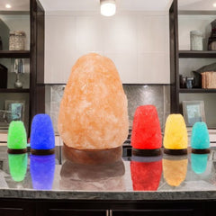 Natural Himalayan salt lamp beside five smaller USB colour-changing salt lamps in green, blue, red, yellow and teal on a kitchen counter