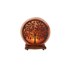 Round tree-of-life wood and salt lamp glowing amber against a white background