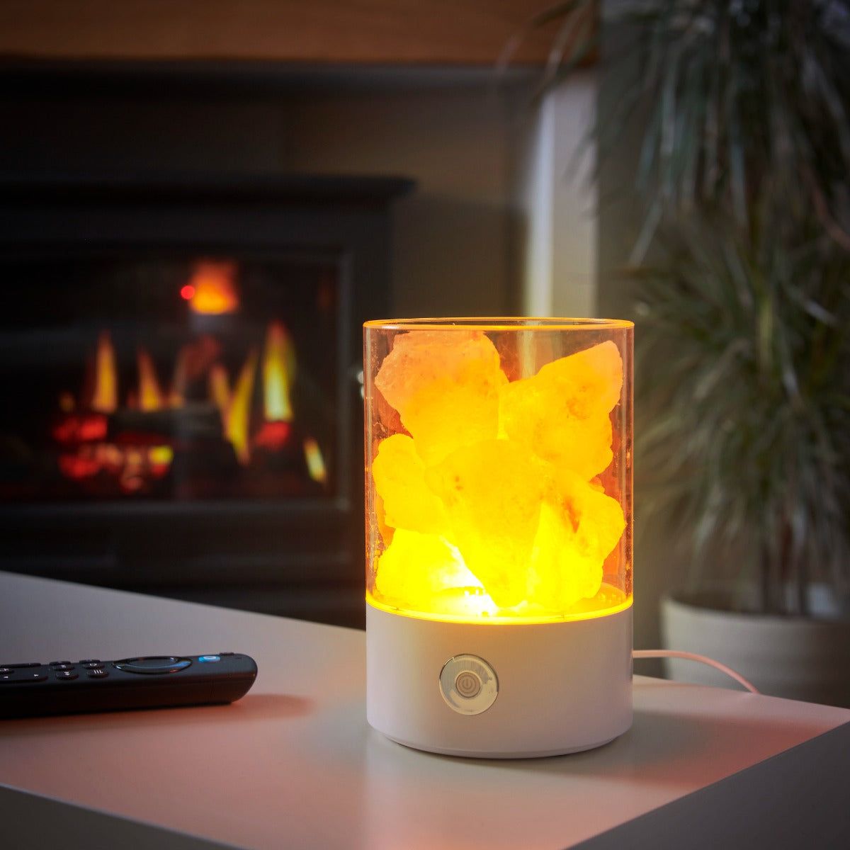 USB salt crystal lamp glowing amber on a shelf beside a lit fireplace and a TV remote