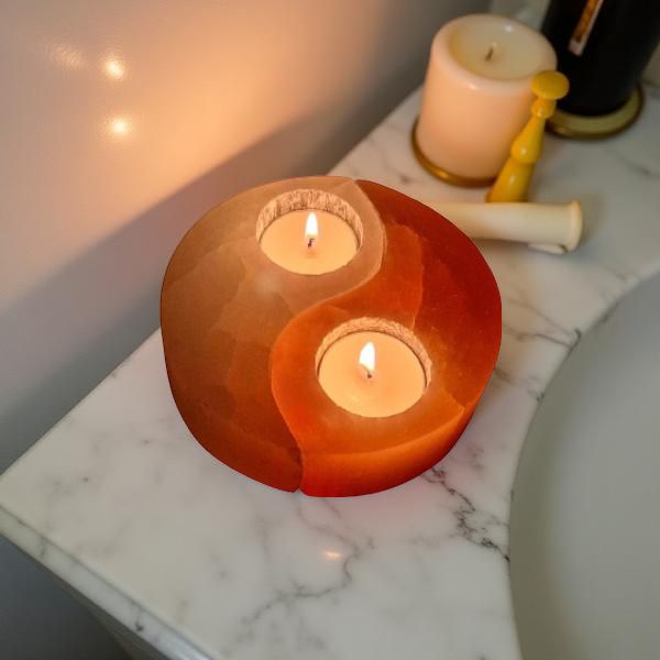 Pink and white Himalayan salt yin yang candle holder with two lit tealights on a bathroom counter