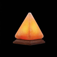 Pyramid-shaped Himalayan salt USB lamp glowing amber on a wooden base against a black background