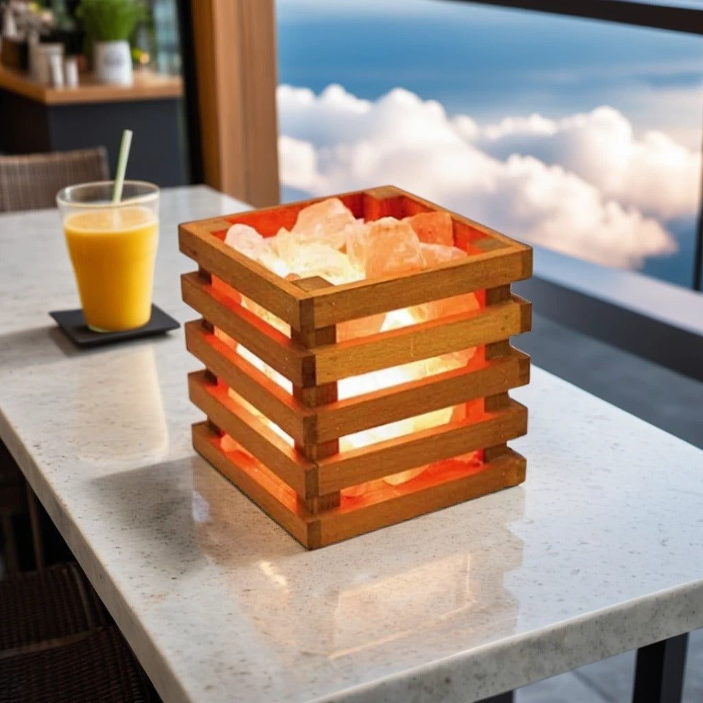 Square wood-slat salt lamp filled with glowing Himalayan salt chunks on a rooftop cafe table beside a glass of orange juice