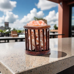 Cylindrical wood-cage salt lamp filled with pink Himalayan salt chunks on an outdoor stone counter