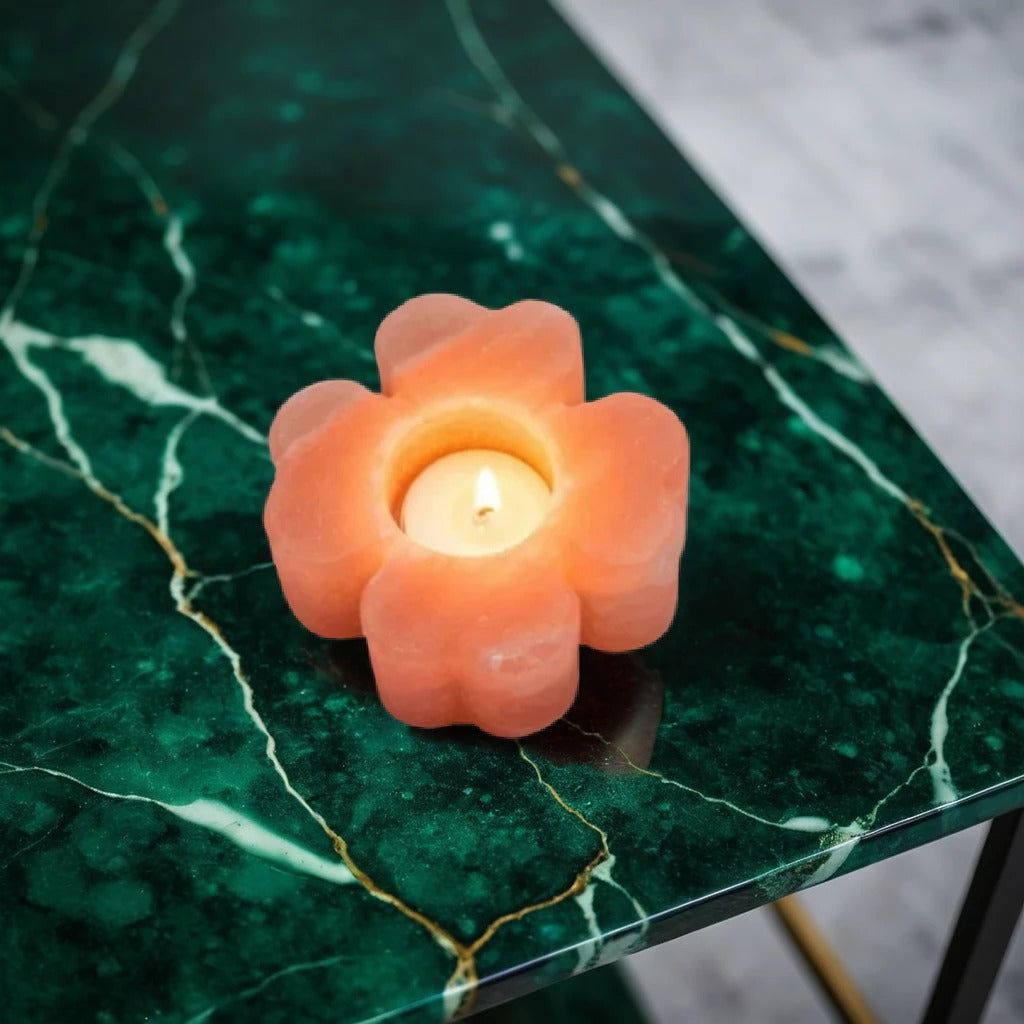 Flower-shaped Himalayan salt candle holder with a lit tealight on a green marble table