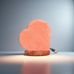 Heart-shaped Himalayan salt USB lamp on a wooden base against a dark blue backdrop