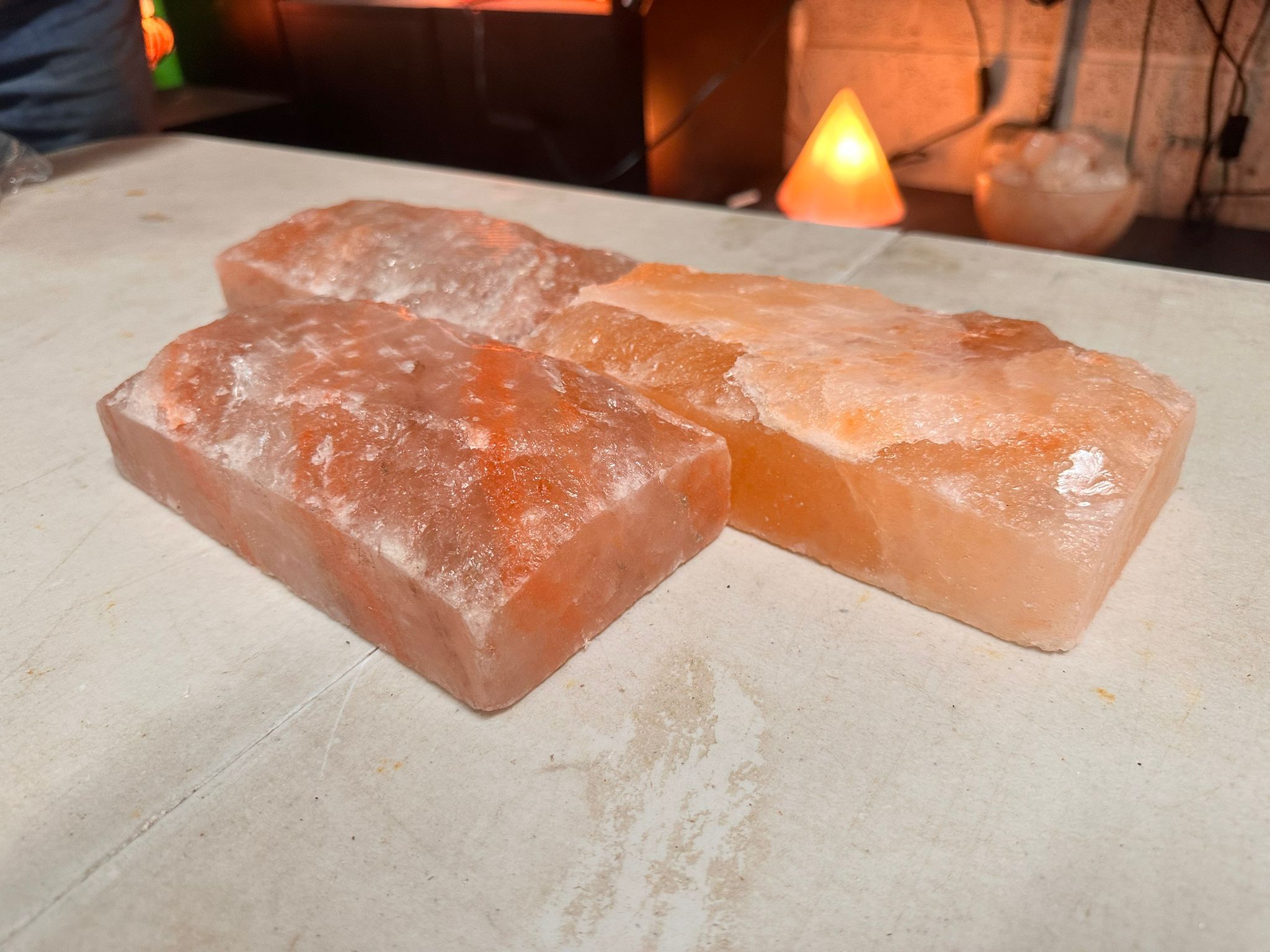 Two Himalayan salt tiles beside a lit pyramid-shaped salt lamp