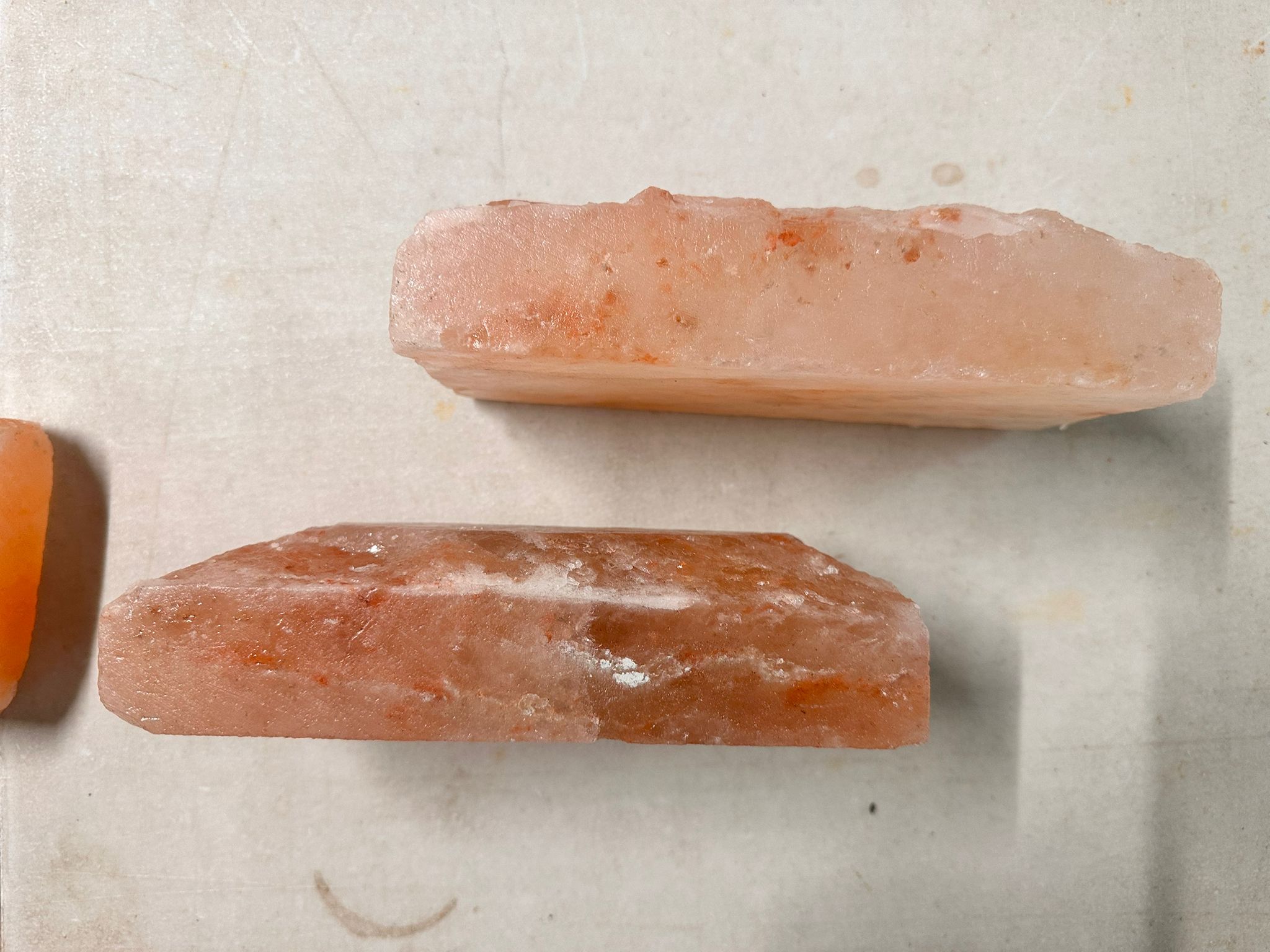 Two thin Himalayan salt tiles lying side by side, showing natural pink and white veining