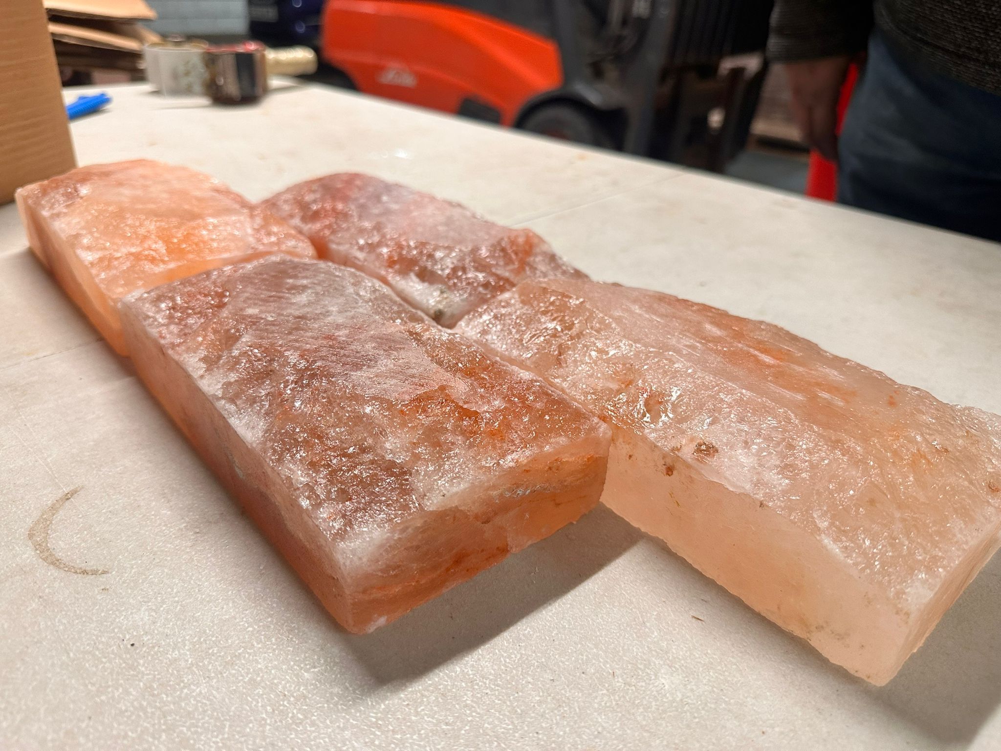 Four Himalayan salt tiles stacked at an angle on a warehouse table