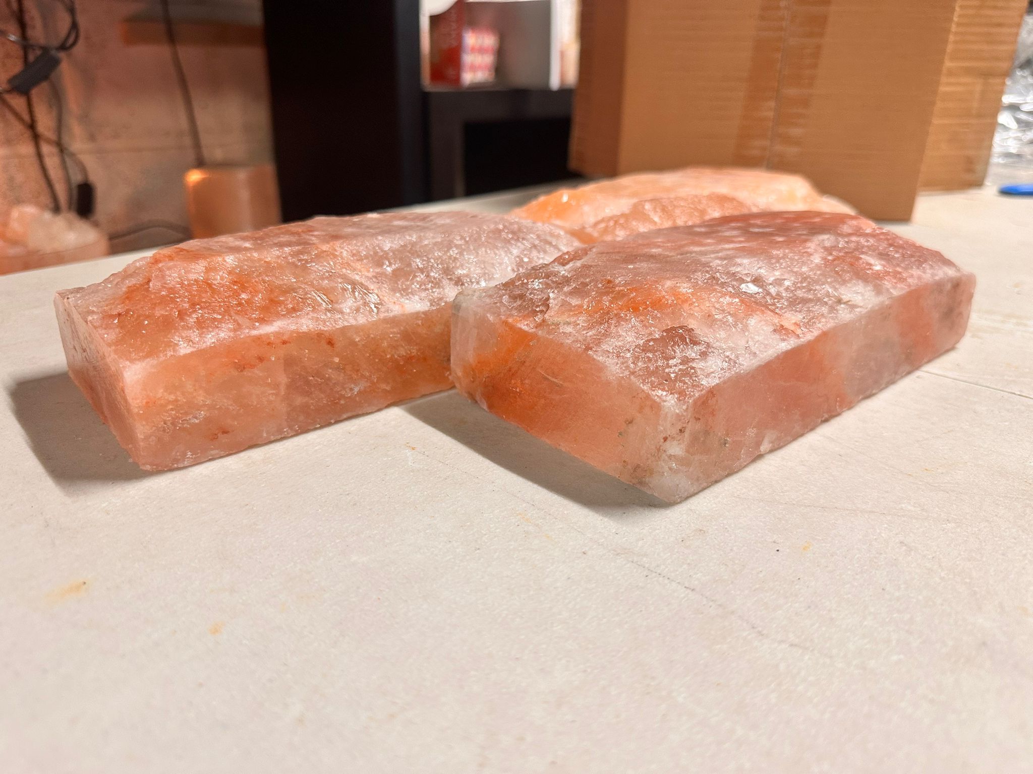 Two Himalayan salt tiles resting on a table with a cardboard box in the background