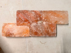 Four Himalayan salt tiles arranged in a brick-wall pattern on a warehouse table